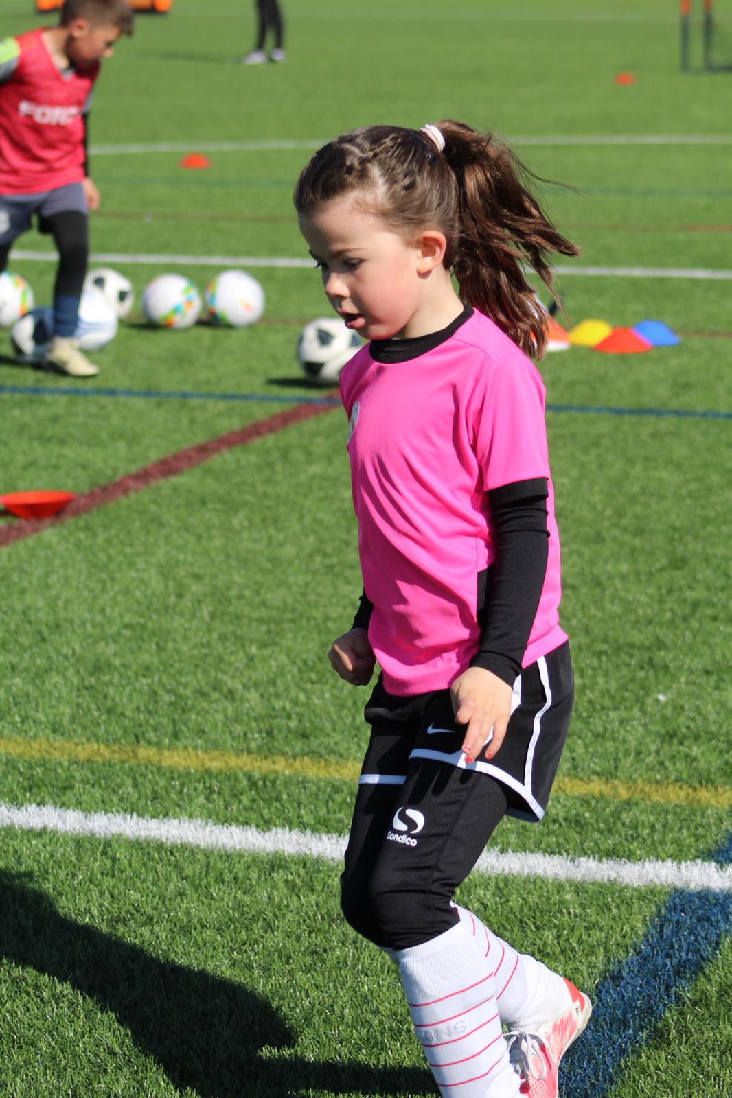 Young girl running with a football during a JCSS coaching session in Skegness