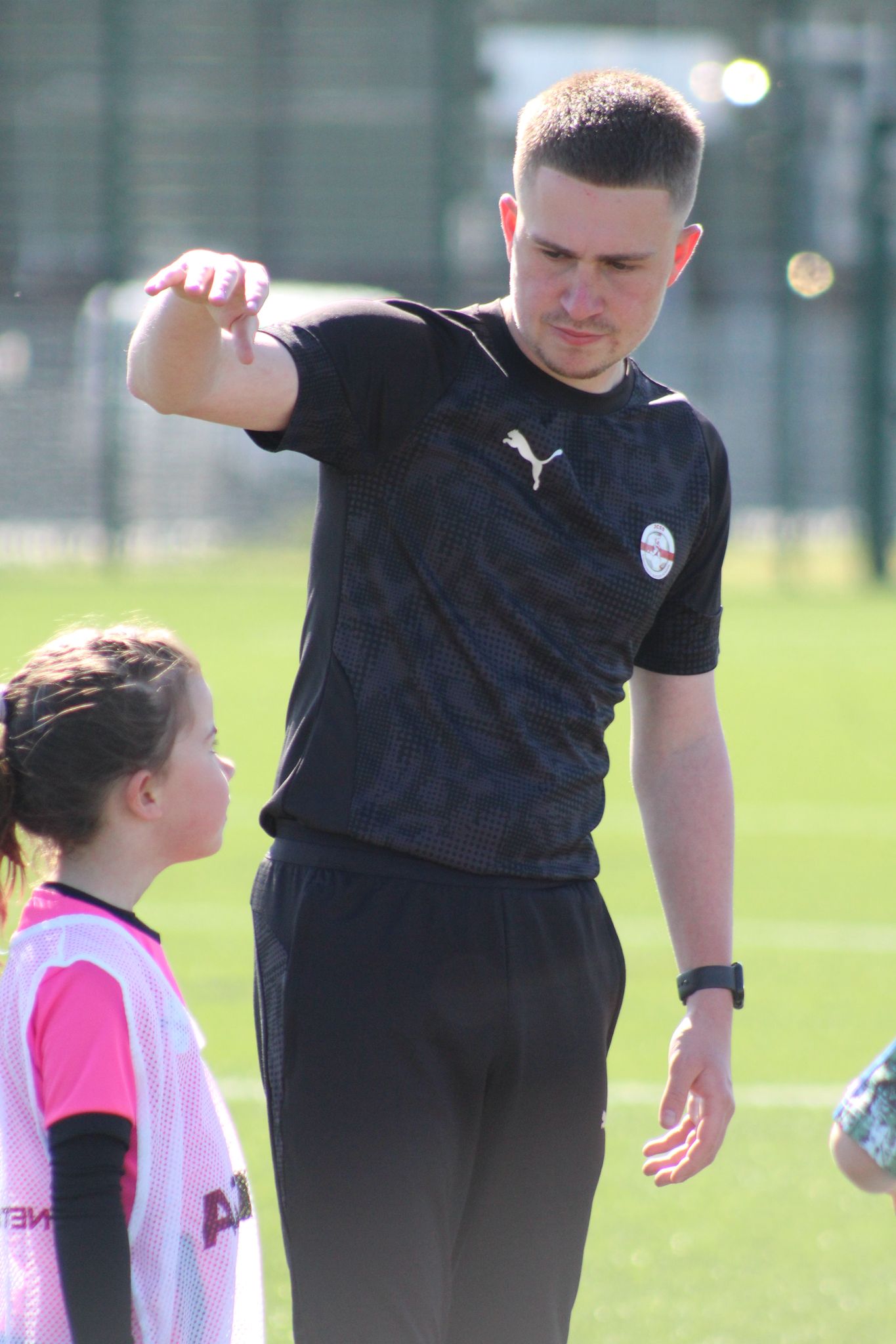 one of the expert coaches at jcss coaching a young girl in the football holiday camp