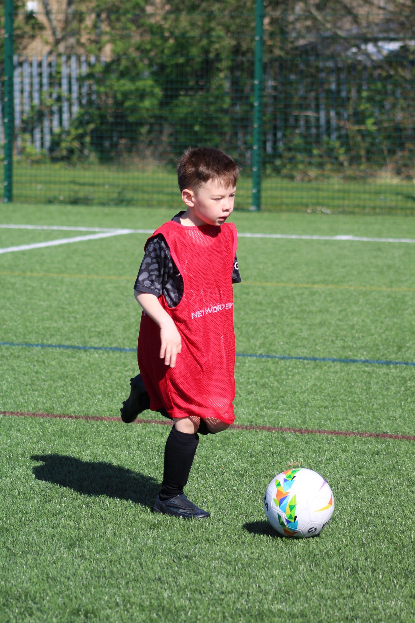 young child in a playmakers session dribbling a football