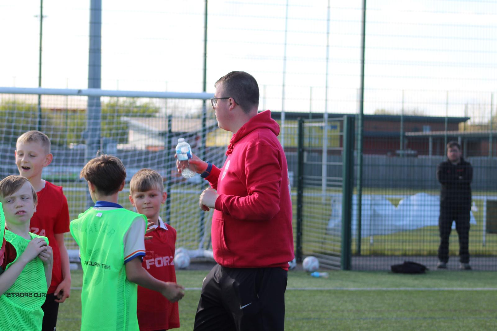 main coach jack giving insturctions to a group of children at the playmakers session
