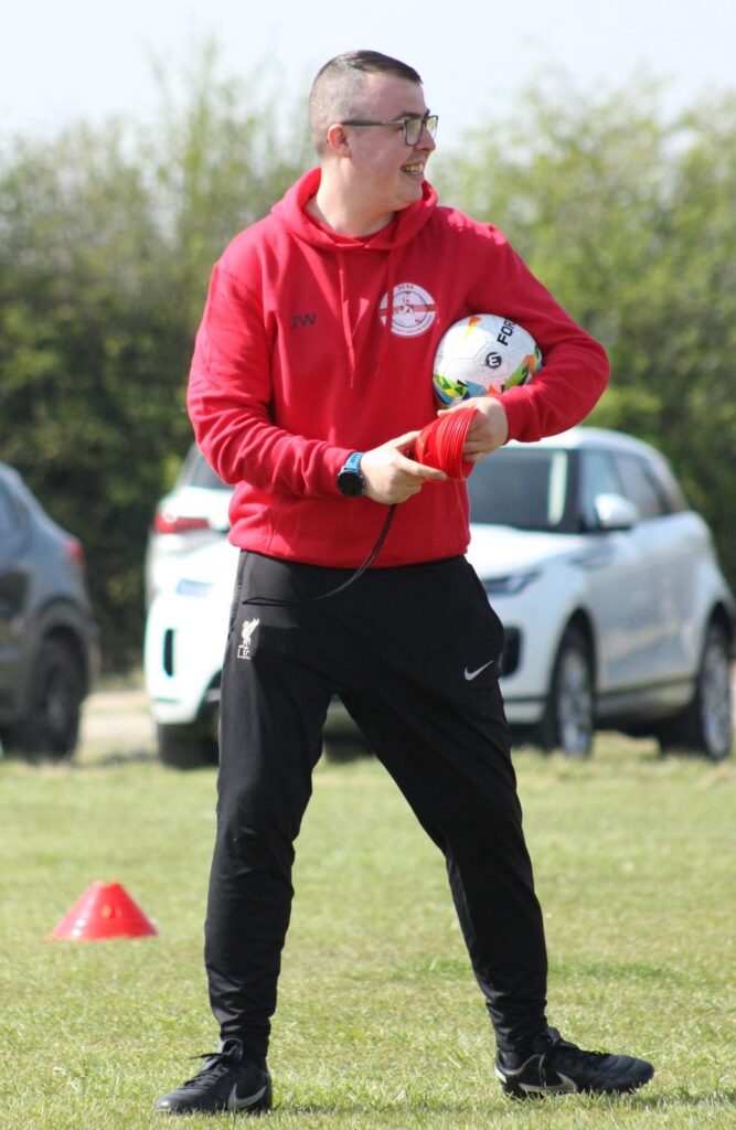 Jack, JCSS head coach, standing with a football and giving instructions to young players during a training session in Skegness