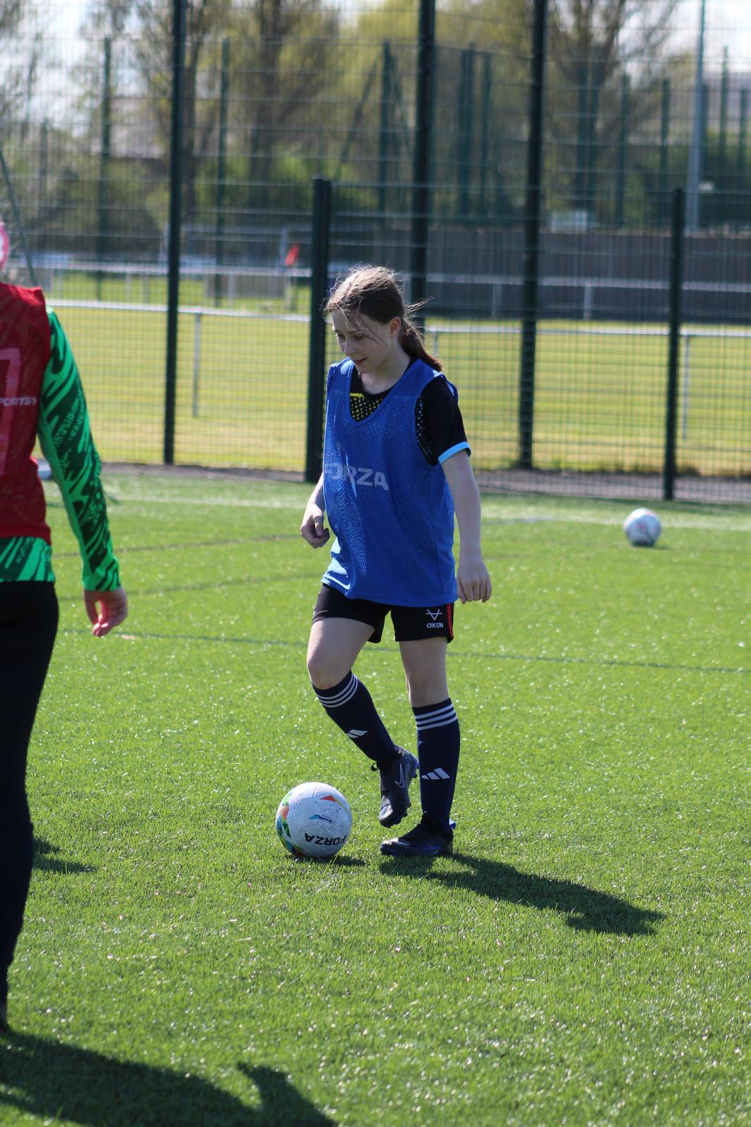 girl in development+ football holiday camp facing a defender with the football